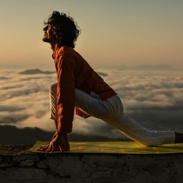 Silhouette of a man stretching against a sunrise.